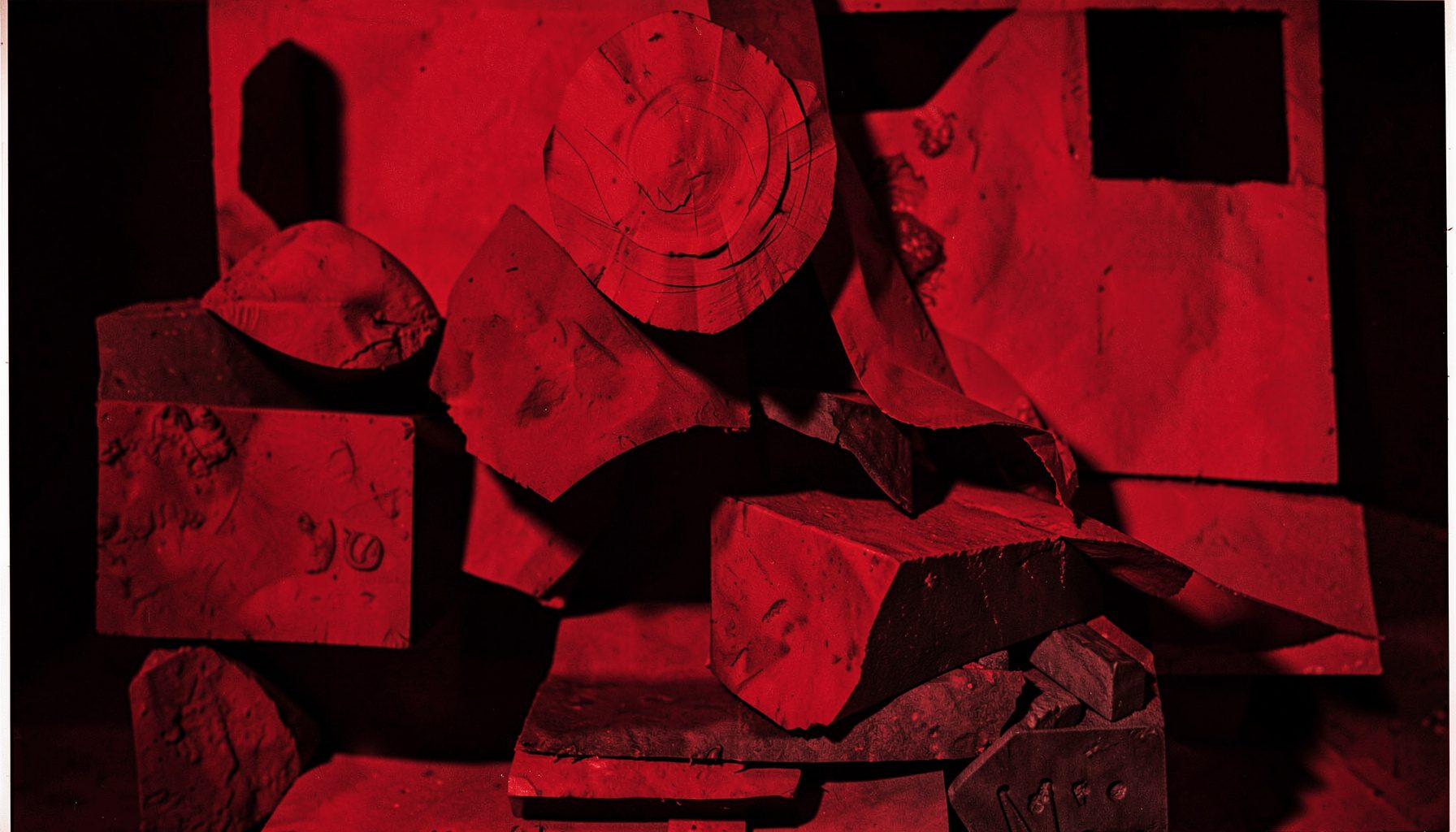 Duotone red-and-black photograph of an art installation or visual artwork with layered textures and bold graphic forms