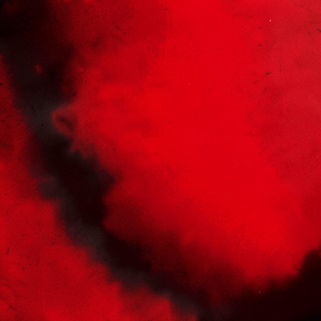 A performer mid-motion on stage, dramatic red spotlight, duotone black and red