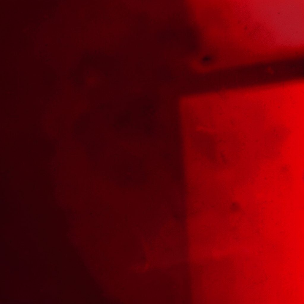 Vivid red-black duotone photograph with prismatic light, suggesting energy and spectrum